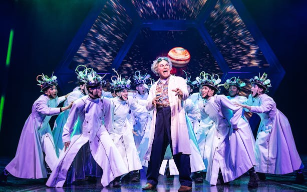 Cast performing a scene from Back to the Future the Musical with futuristic costumes.