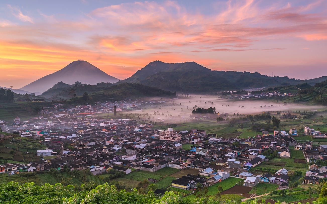 Dieng Plateau at sunrise with mist over the village, seen on a guided tour from Yogyakarta.