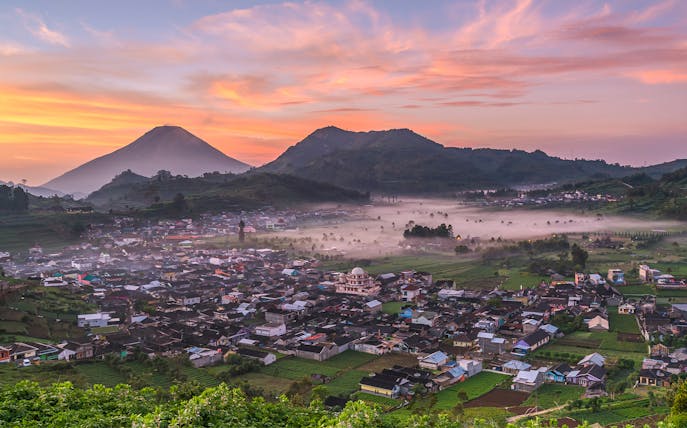 Dieng Plateau at sunrise with mist over the village, seen on a guided tour from Yogyakarta.