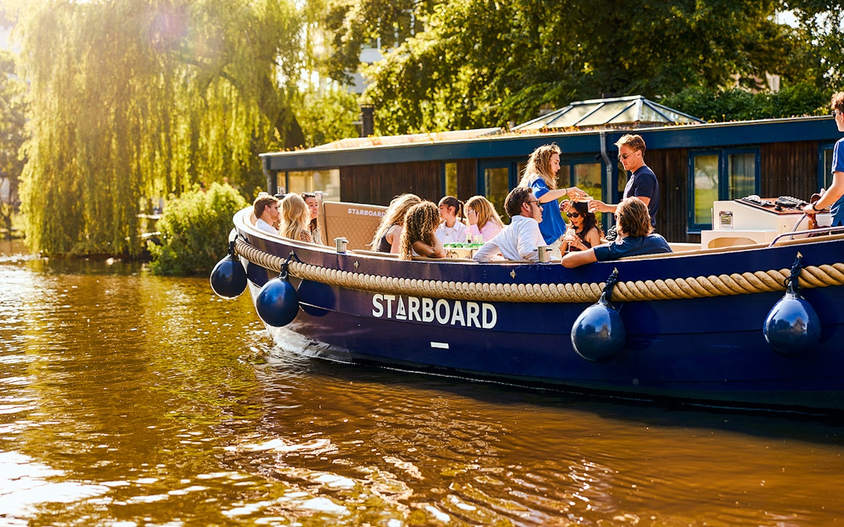 Luxury canal cruise boat with passengers enjoying a sunny day in Amsterdam.