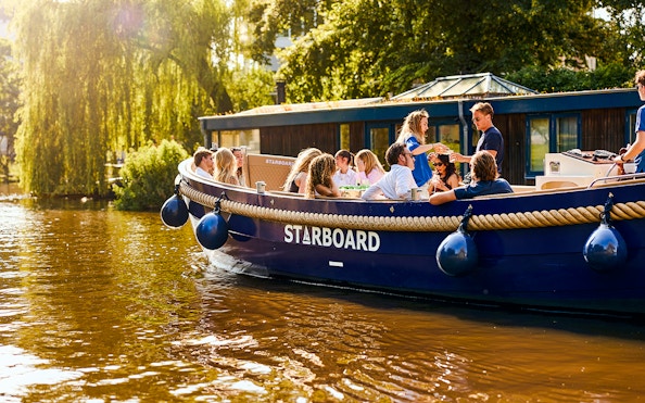 Luxury canal cruise boat with passengers enjoying a sunny day in Amsterdam.