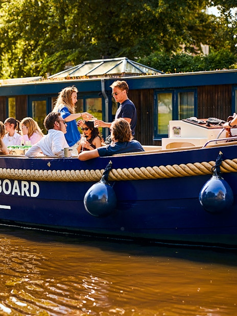 Luxury canal cruise boat with passengers enjoying a sunny day in Amsterdam.