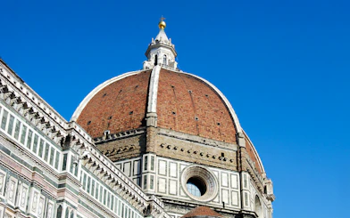 Florence Duomo's iconic red-tiled dome against a clear blue sky.