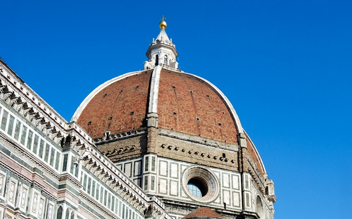 Florence Duomo's iconic red-tiled dome against a clear blue sky.