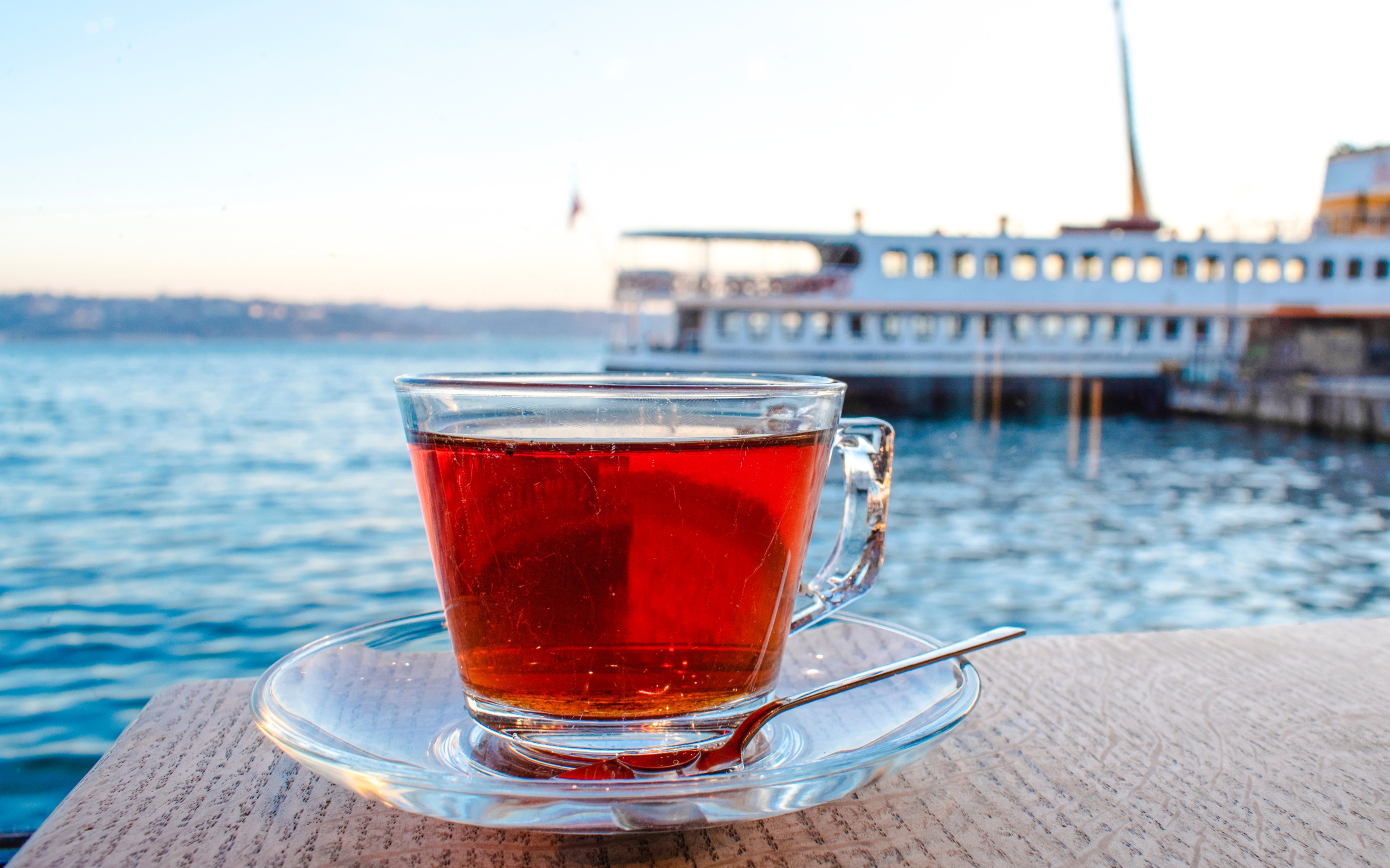Cup of tea on a table with a cruise ship in the background on a sunny day.