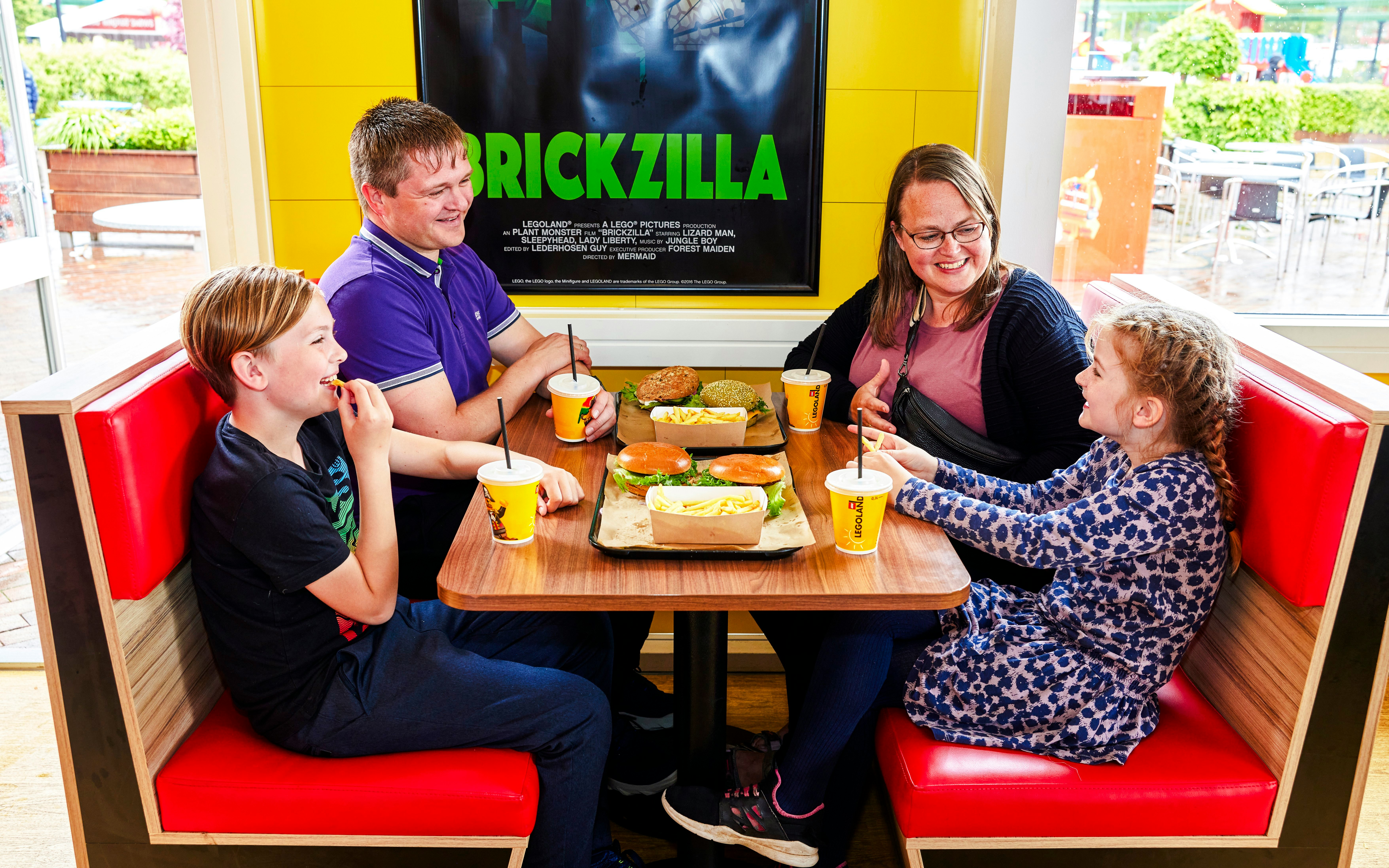 Family dining at a cafe in LEGOLAND Billund with burgers and drinks.