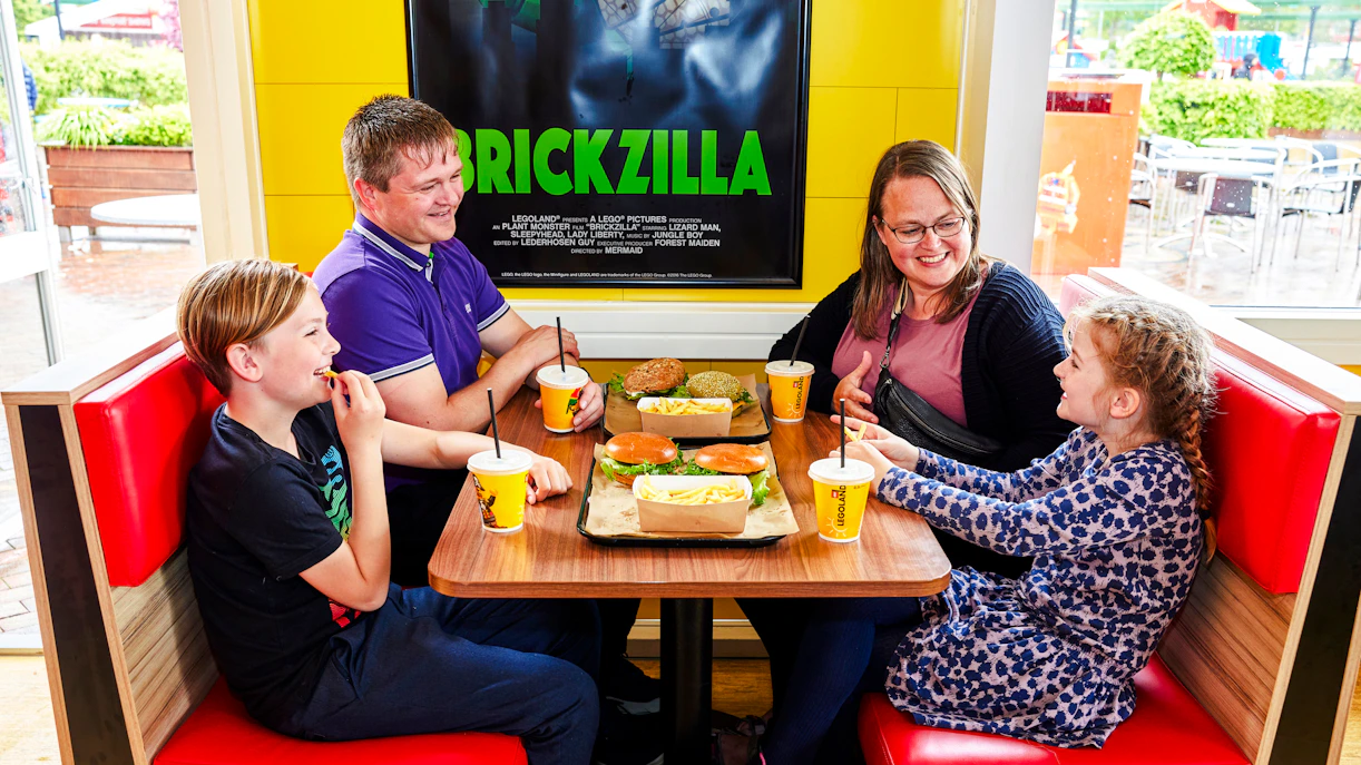 Family dining at a cafe in LEGOLAND Billund with burgers and drinks.