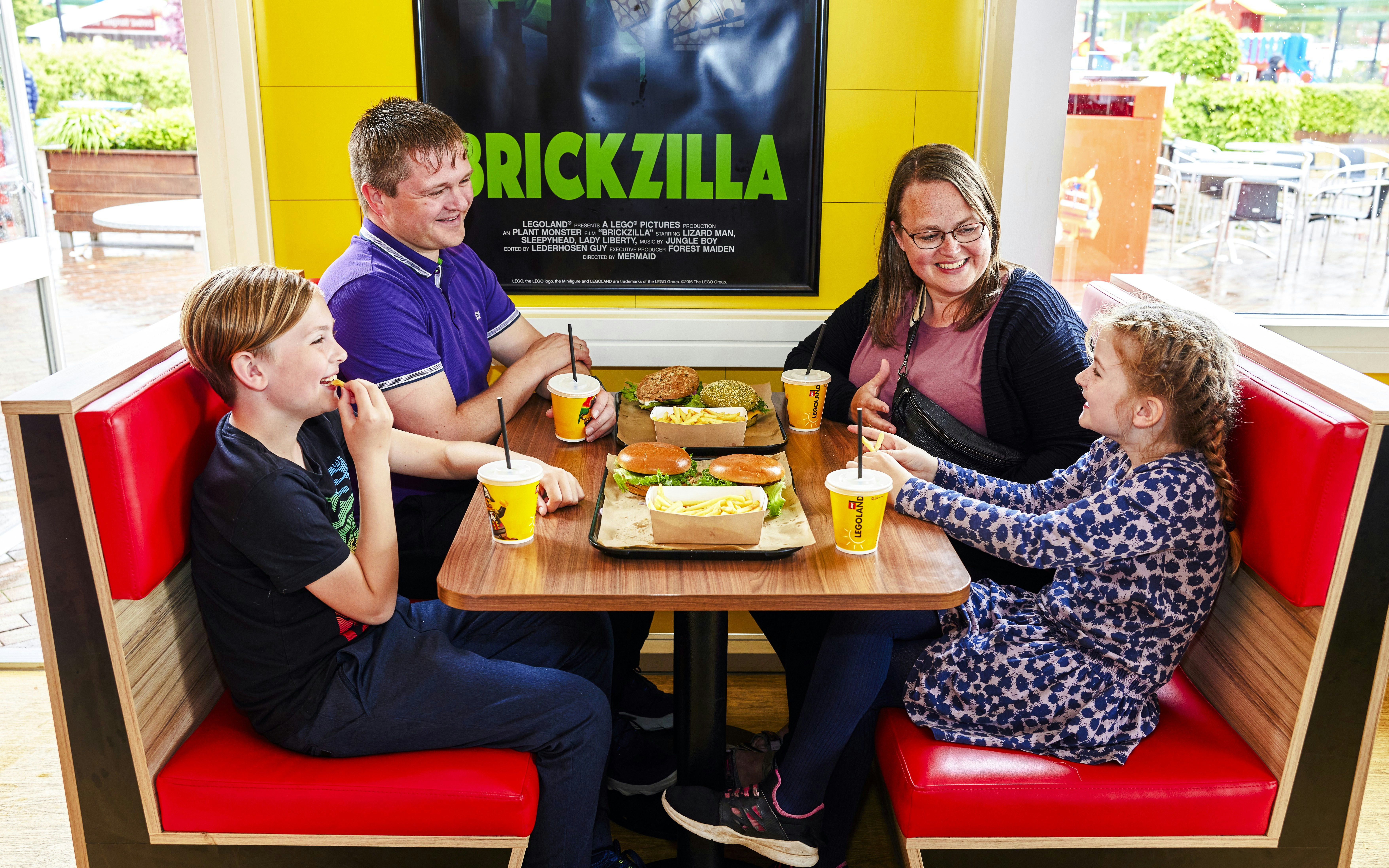 Family dining at a cafe in LEGOLAND Billund with burgers and drinks.
