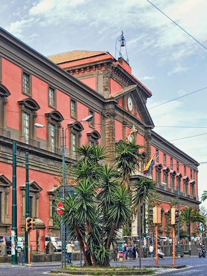 Naples National Archaeological Museum exterior with palm trees and street view.