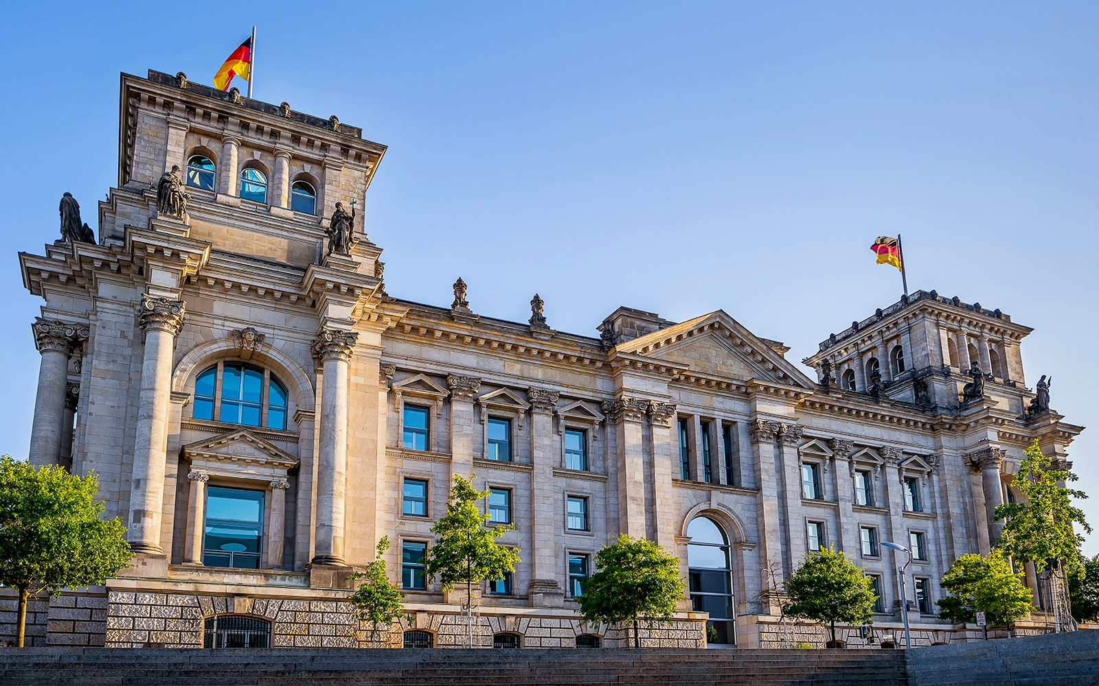 Reichstag building in Berlin with German flags, featured in guided tours.