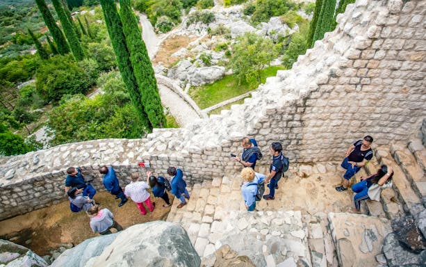 Tour group exploring ancient stone walls at Skol Grad, Croatia.