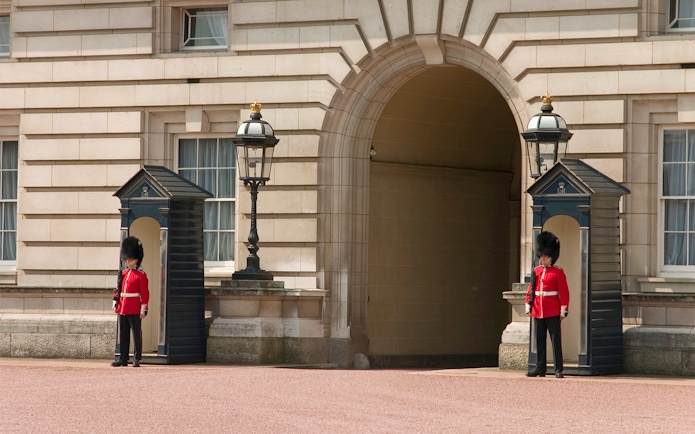 Guards in red uniforms at Buckingham Palace entrance, London.