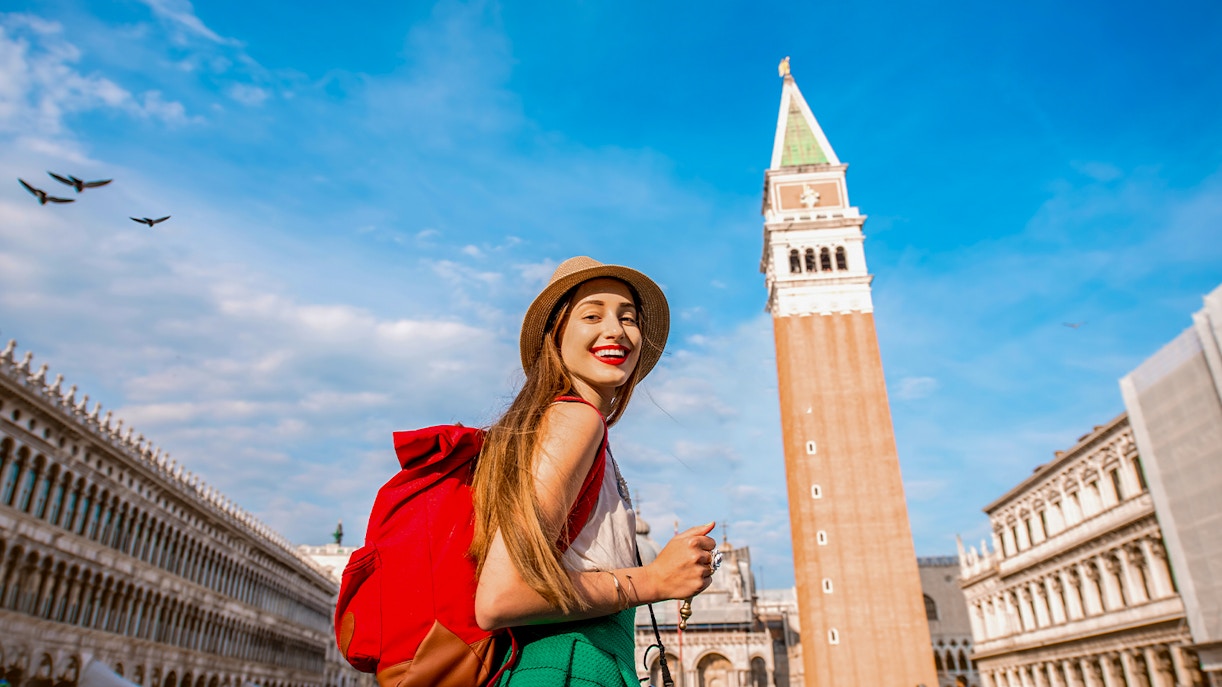 St Mark's Bell Tower in San Marco Square, Venice, with tourists exploring the historic site.