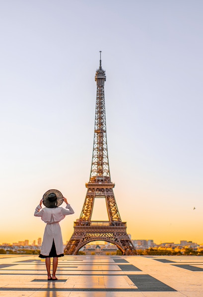 Person standing in front of the Eiffel Tower at sunrise, Paris.