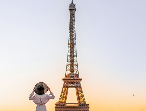 Person standing in front of the Eiffel Tower at sunrise, Paris.