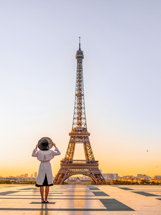 Person standing in front of the Eiffel Tower at sunrise, Paris.