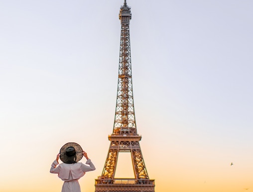Person standing in front of the Eiffel Tower at sunrise, Paris.