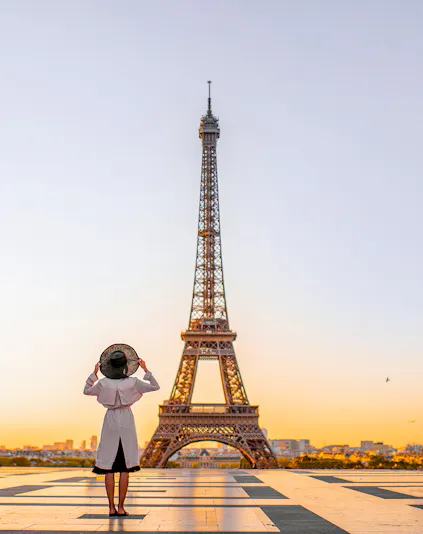 Person standing in front of the Eiffel Tower at sunrise, Paris.