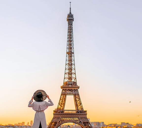 Person standing in front of the Eiffel Tower at sunrise, Paris.