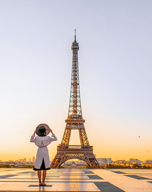 Person standing in front of the Eiffel Tower at sunrise, Paris.
