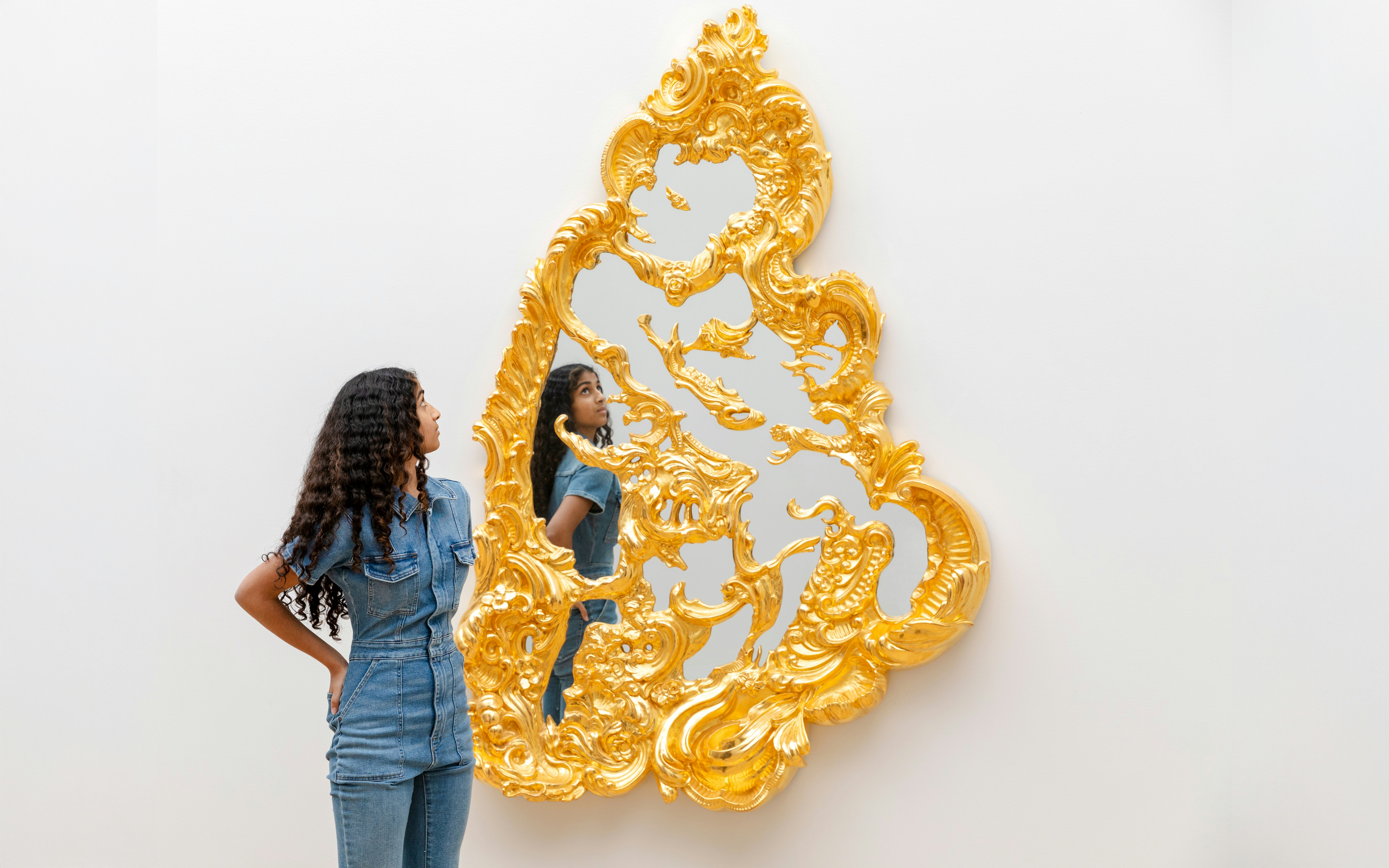 Woman admiring golden mirror installation at Art Institute of Chicago, Chicago