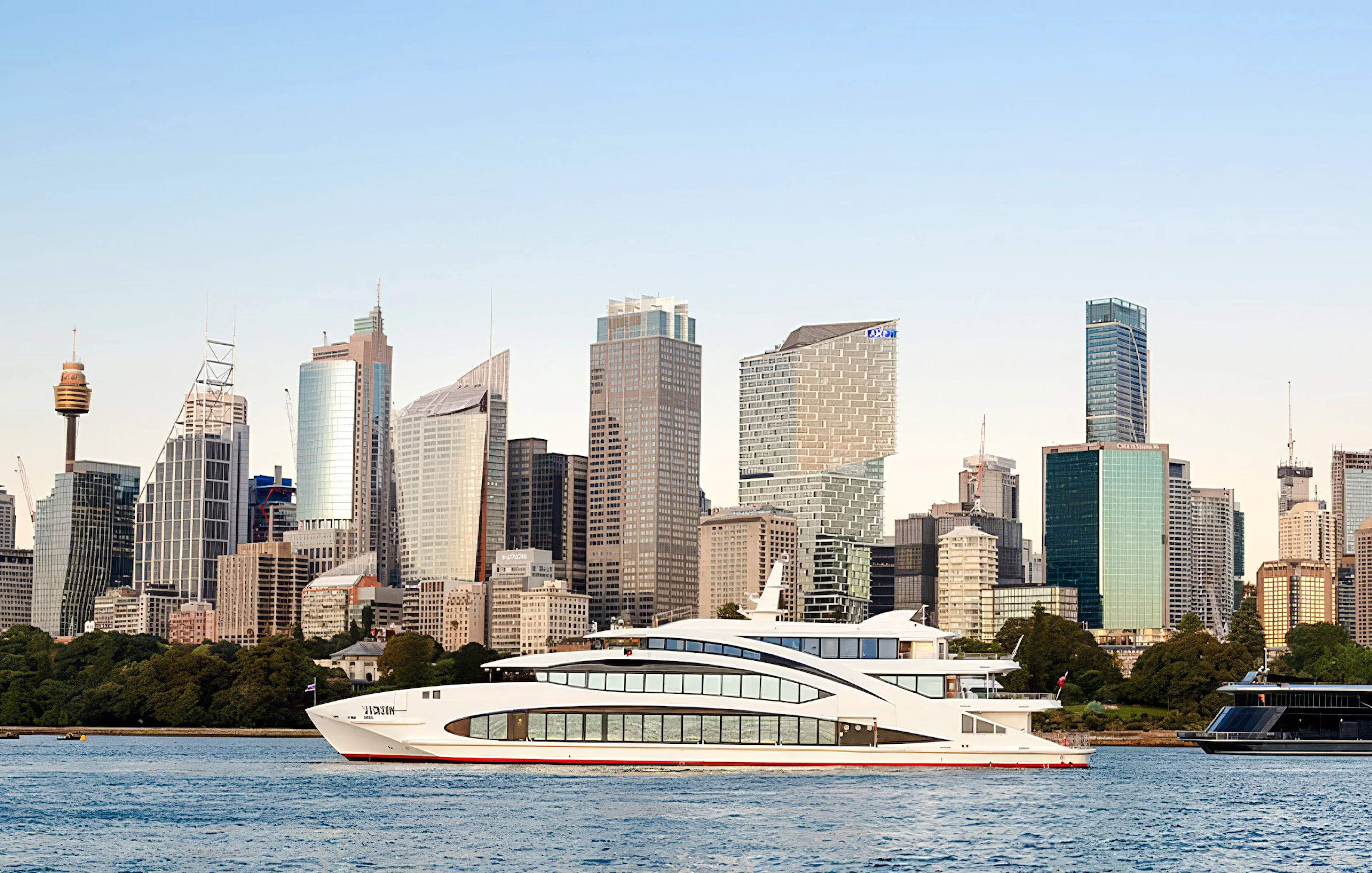 Luxury yacht The Jackson cruising in Sydney Harbour with city skyline backdrop.