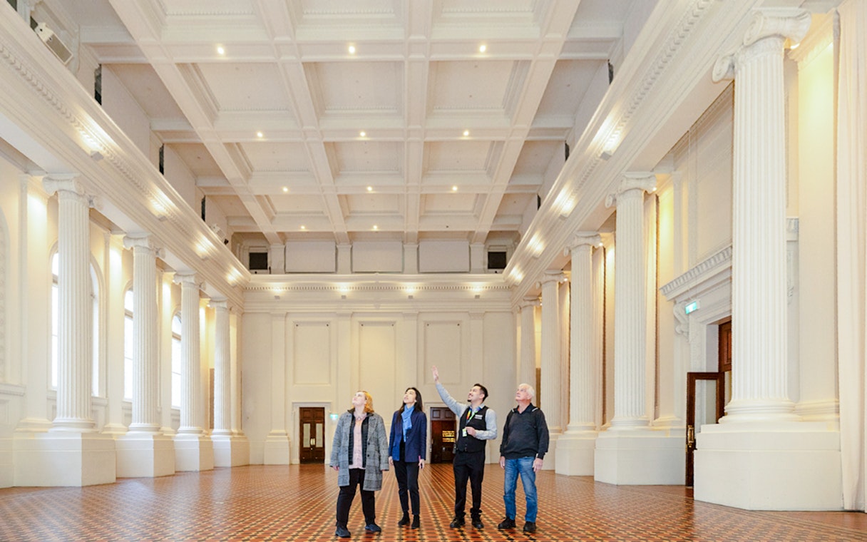 Visitors on a guided tour inside the grand hall of the Immigration Museum.