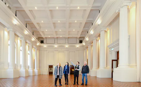 Visitors on a guided tour inside the grand hall of the Immigration Museum.