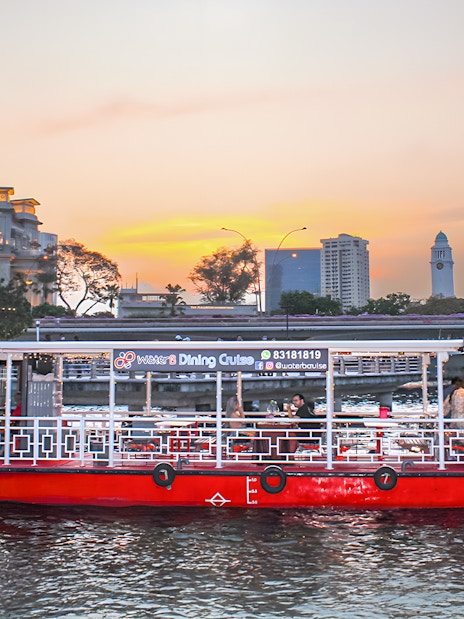 Singapore River Cruise boat by WaterB passing Merlion Park at sunset.