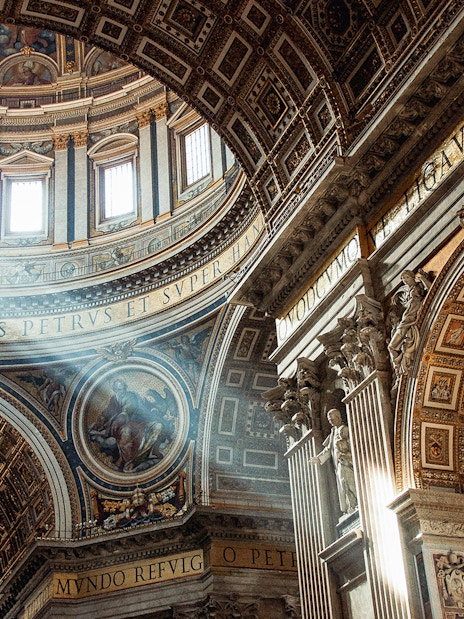 St. Peter’s Basilica interior with ornate ceiling and sunlight streaming through windows.
