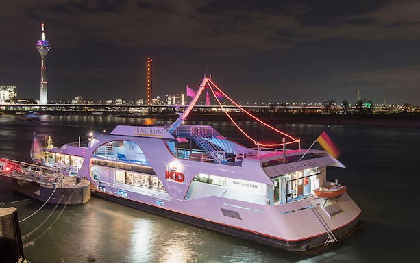 Cruise ship on the Rhine River at night with Düsseldorf skyline in the background.