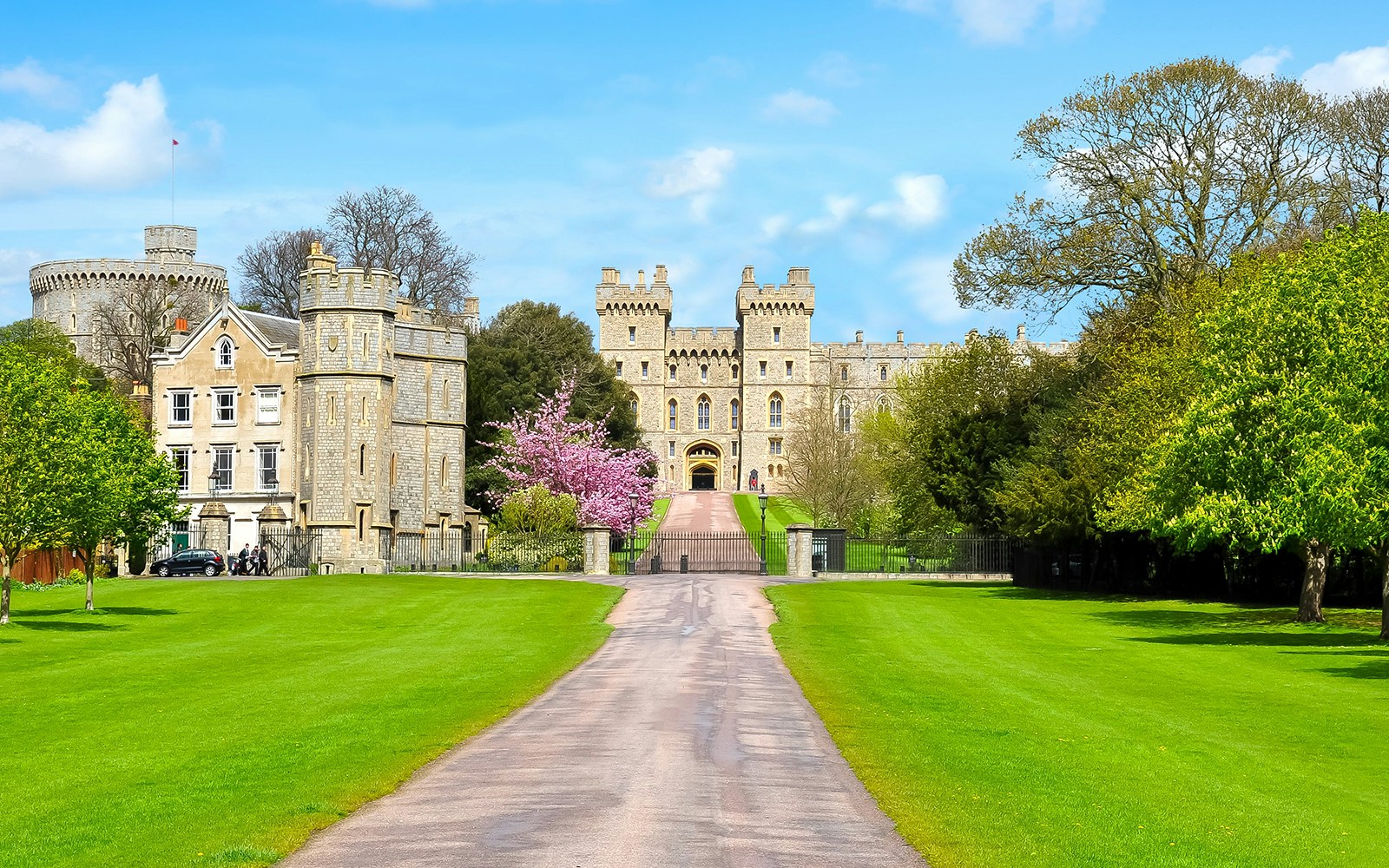 Windsor Castle exterior with stone towers and lush green gardens.