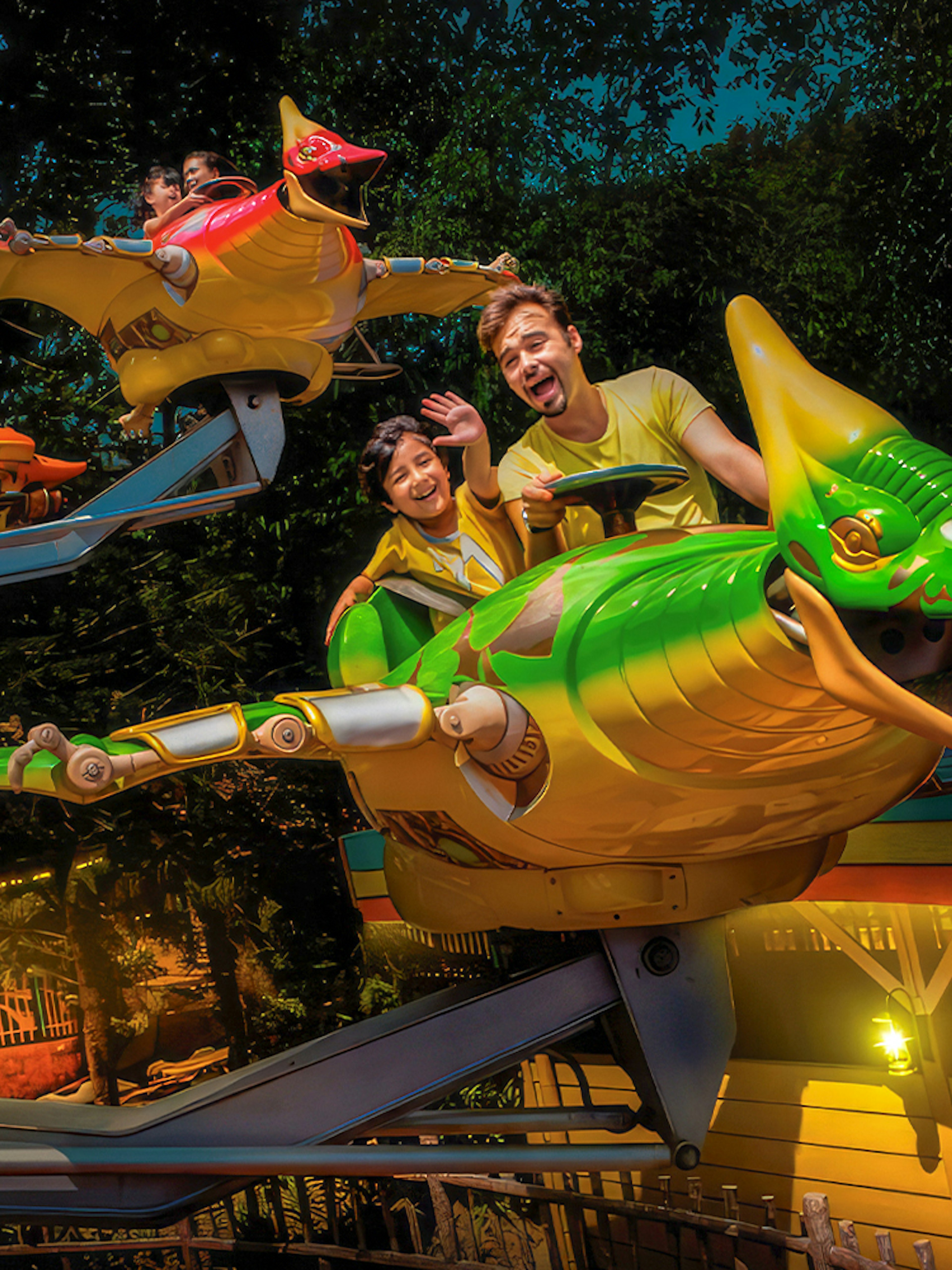 Father and son enjoying Flying Dinosaur ride at theme park.