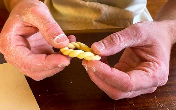 Hands shaping traditional Sardinian pasta during a workshop in Olbia.