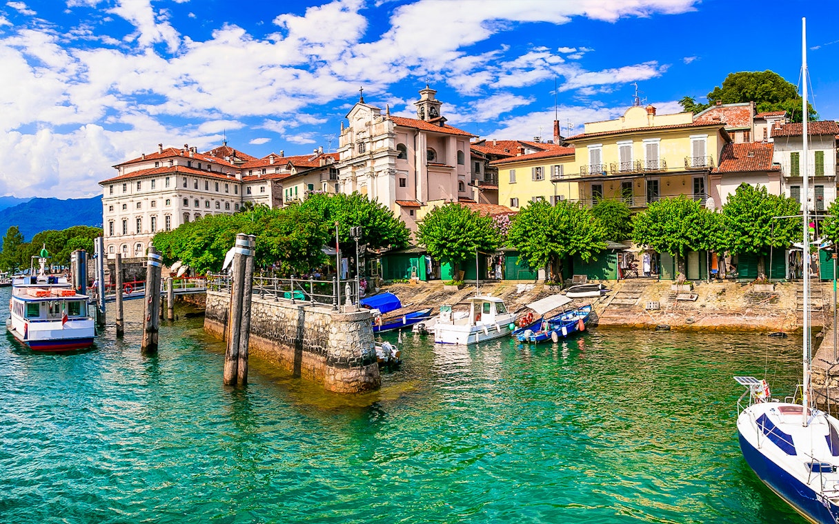 Hop-on hop-off boat docked at Isole Borromee with historic buildings in the background.