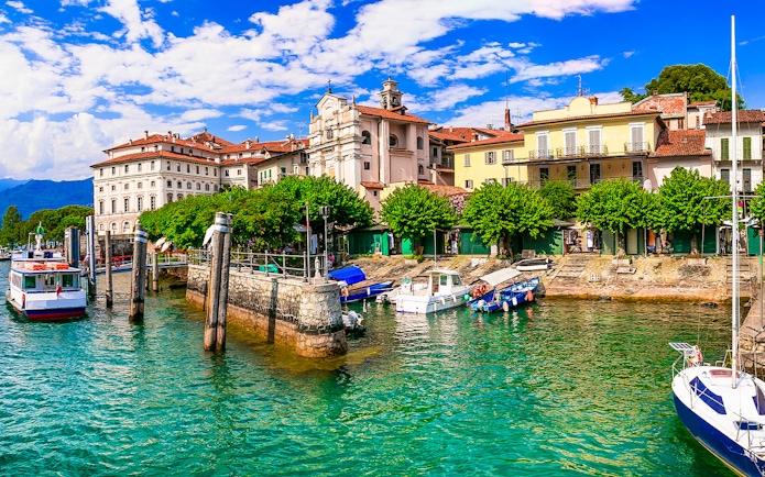 Hop-on hop-off boat docked at Isole Borromee with historic buildings in the background.