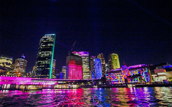 Lit up buildings in Sydney Harbour during Vivid Sydney Cruise.