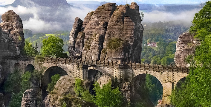 Bastei Bridge in Saxon Switzerland with sandstone rock formations and lush greenery.