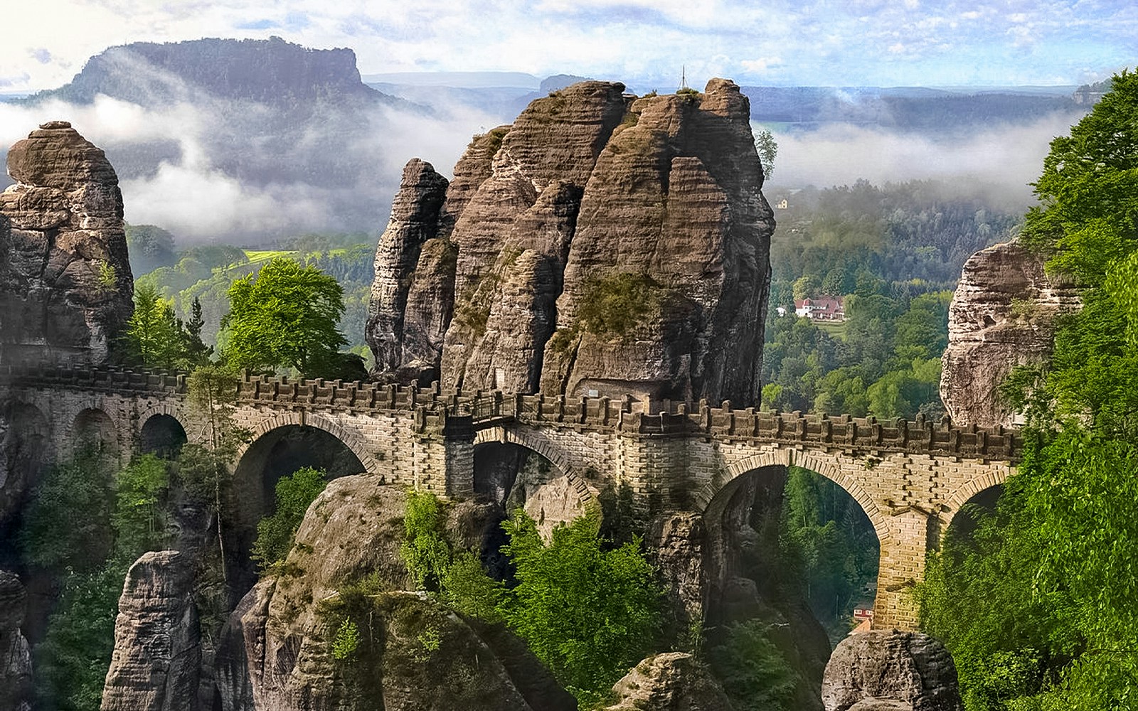 Hikers on a trail with rock formations in Bohemian and Saxon Switzerland National Park.