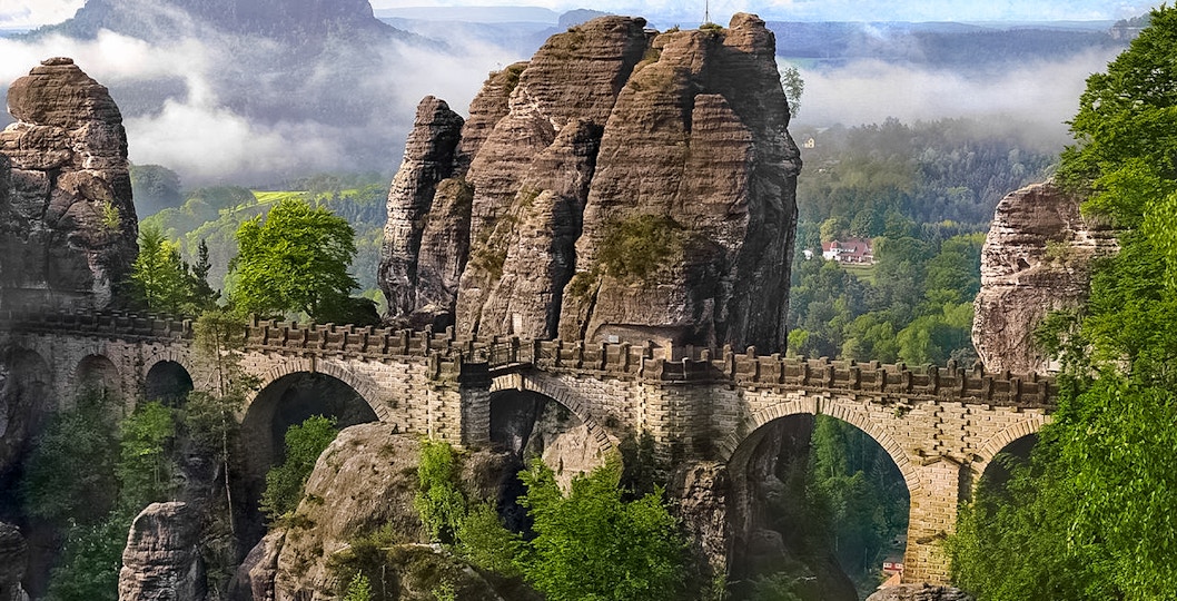 Bastei Bridge in Saxon Switzerland with sandstone rock formations and lush greenery.