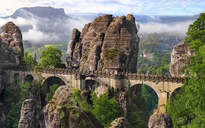 Bastei Bridge in Saxon Switzerland with sandstone rock formations and lush greenery.
