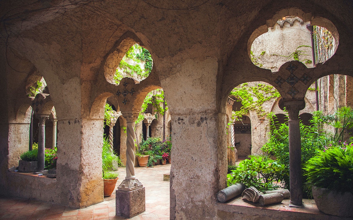 Medieval cloister with arches and greenery, Amalfi Coast.