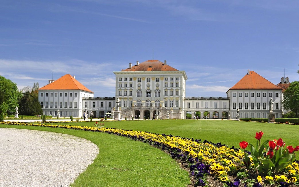 Nymphenburg Palace in Munich with gardens and colorful flowers.