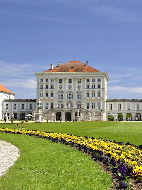 Nymphenburg Palace in Munich with gardens and colorful flowers.