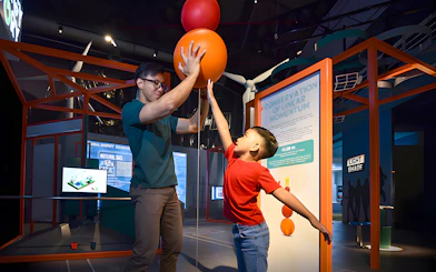 Child and adult interacting with a physics exhibit at Science Centre Singapore.
