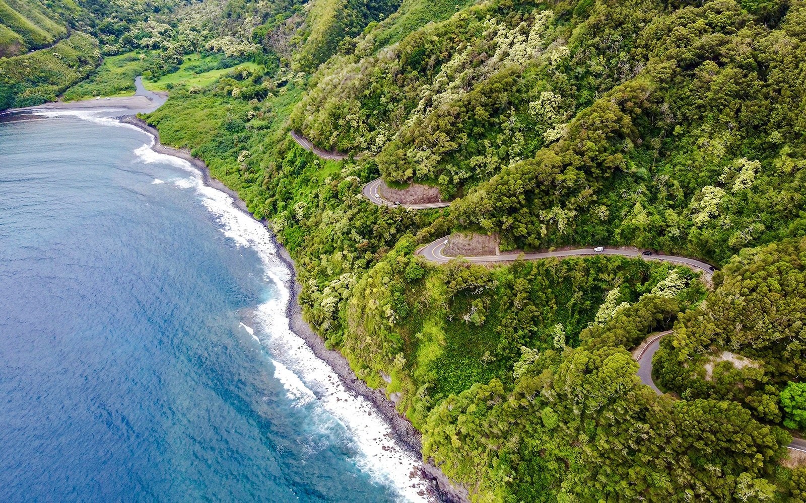Winding coastal road through lush greenery on the Road to Hana, Maui, Hawaii.