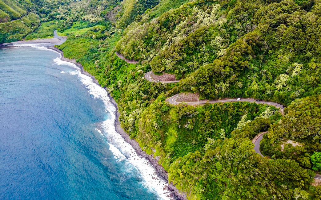 Winding coastal road through lush greenery on the Road to Hana, Maui, Hawaii.