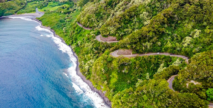 Winding coastal road through lush greenery on the Road to Hana, Maui, Hawaii.