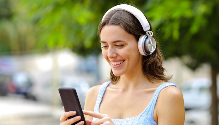 Woman using audio guide on smartphone with headphones outdoors.Woman using audio guide on smartphone with headphones outdoors.