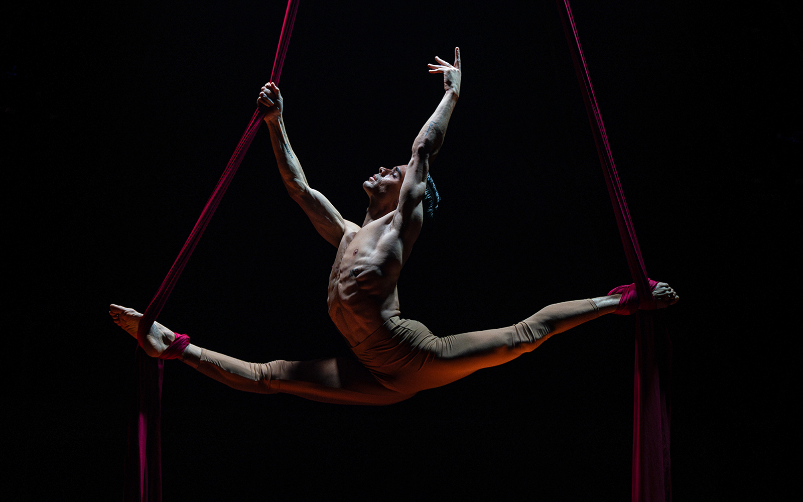 Aerial performer in mid-air split during La Clique show.